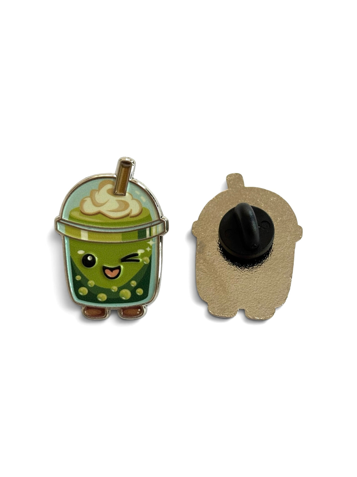 A cute enamel pin shaped like a winking green bubble matcha drink cup with whipped cream and a straw, shown next to its metal backing with a black pin clasp.